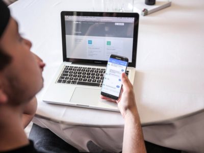 guy holding a phone while checking his laptop