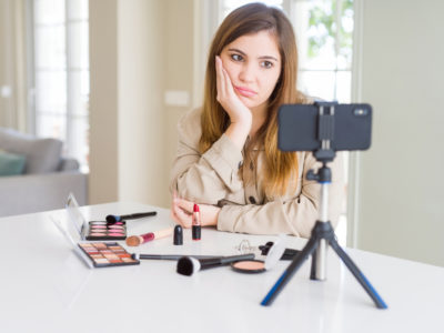 Young influencer woman recording make up video tutorial with annoyed expression